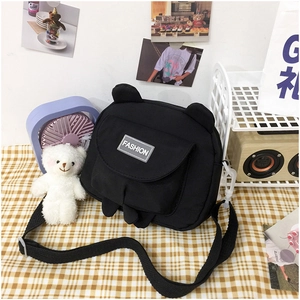 Detail of cute black canvas bear crossbody bag with fashion label and bear ears design