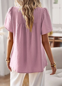 Detail view of pink short-sleeve top featuring dot texture and back pleated design