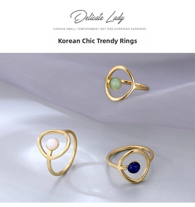Detalle de tres anillos dorados minimalistas con cuentas verde esmeralda, blancas y azul lapis