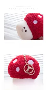 Detail of red plush mushroom pendant with soft texture, smiling face and golden metal clasp