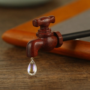 Macro detail of a creative wooden faucet hair stick with a crystal water drop pendant