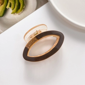 Close-up of brown oval hair claw clip with rhinestones on a clean white surface