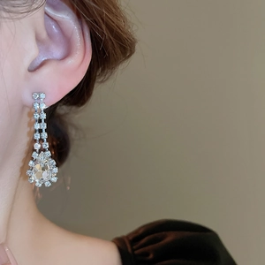 Close-up of silver water drop tassel earring with sparkling crystals on a model's ear