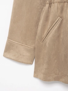 Close-up of cuff stitching and slanted pocket detail on khaki faux suede jacket