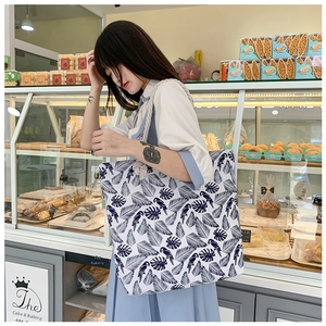 Detailed shot of large floral canvas tote bag with parrot print and rope handles on shoulder