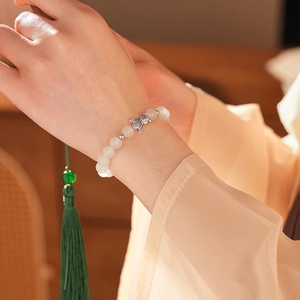 Detail of chalcedony fish bracelet with translucent white beads and green silk tassel