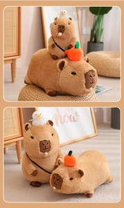 Detail showing plush capybara with green backpack and orange fruit on head