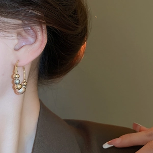 Close-up of gold and silver beaded hoop earrings worn with a professional brown blazer