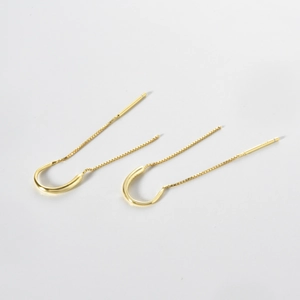 Detail of long gold tassel threader earrings with U-shaped hooks and thin box chains