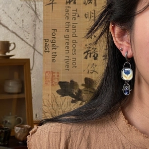 Detailed view of Egyptian style enamel flower earrings with blue teardrop gemstones