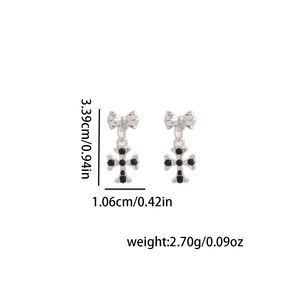 Vue détaillée de boucles d'oreilles nœud croix en argent avec gemmes noires et taille