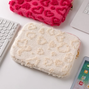 Detail of plush laptop sleeves in rose red and cream with 3D heart patterns and gold zippers