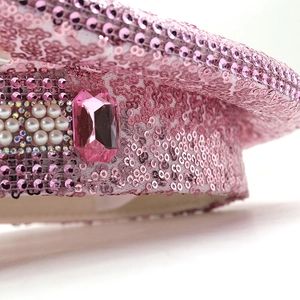 Close-up of pink sequin hat featuring a large crystal gemstone and pearl details