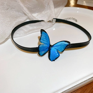 Close-up of a blue gradient butterfly pendant on a black textured choker necklace