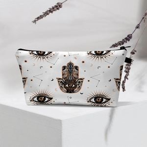 Hamsa Hand makeup bag with evil eye patterns displayed on a white geometric stand