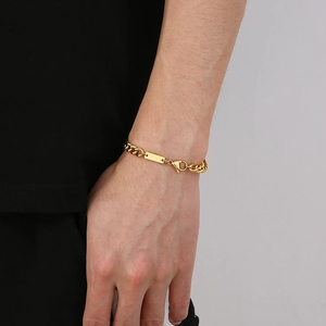 Detail of a gold Cuban link bracelet for men featuring a polished engravable ID plate