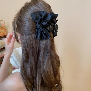 Detail of elegant black satin bow hair claw clip worn for a refined half-up hairstyle