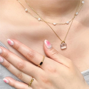 Close-up of elegant stackable gold rings featuring a black square zircon and bow detail