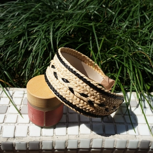 Detailed view of beige raffia braided headband with black woven texture in sunlight