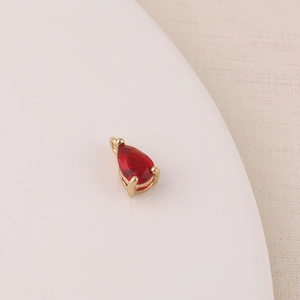 Macro detail of red teardrop zircon pendant with gold-plated claw setting for DIY jewelry