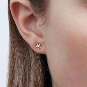 Close-up of a silver flower stud earring with sparkling cubic zirconia on a female model
