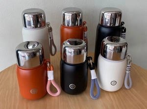 Three colors of matte stainless steel thermal water bottles with portable lanyards on table