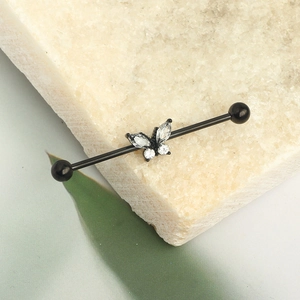 Macro view of black industrial barbell ear piercing with butterfly zircon stone