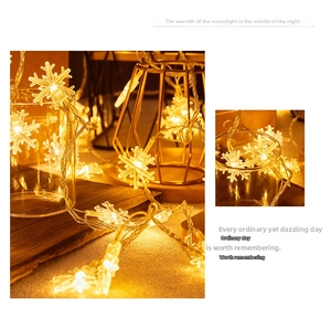 Close-up of warm yellow LED snowflake fairy lights wrapped around a glass and golden stand