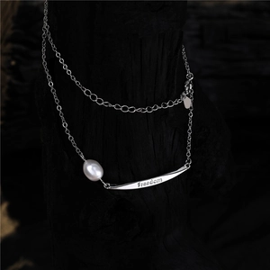 Detail of silver necklace with Freedom engraved metal tube and white freshwater pearl
