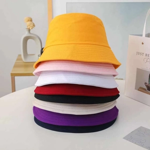 Stack of colorful cotton bucket hats in various shades on a minimalist background