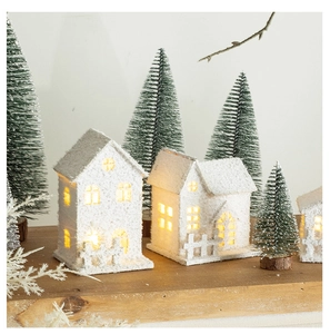 Detail of glowing wooden Christmas cabins with white snow texture on a wooden surface