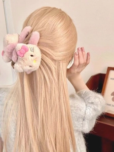 Detail showing the white plush cat hair claw clip with pink bow worn on long blonde hair