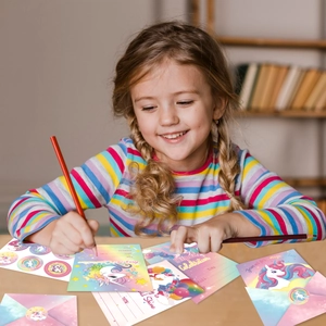 Unicorn party invitation set with envelopes and stickers being filled by a child