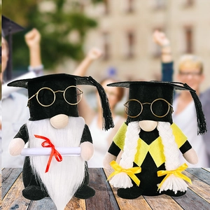 Detailed view of graduation gnomes with black mortarboards and golden glasses on wood