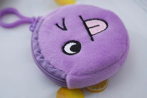Macro shot of purple plush coin purse with embroidery detail and metal keychain
