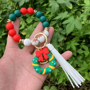 Detail of Christmas silicone bead keychain with green wreath charm and white tassel pendant