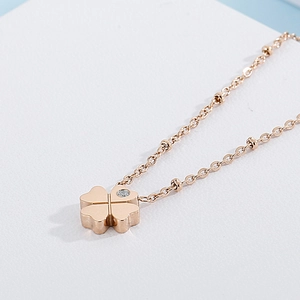 Macro shot of rose gold four-leaf clover pendant with sparkling crystal inlay on beaded chain