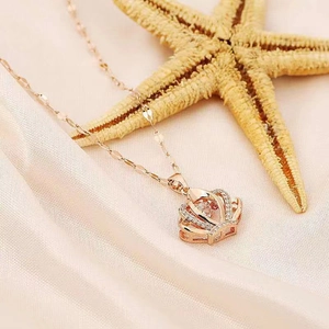 Close-up of rose gold crown pendant with micro-set diamonds on pink silk fabric