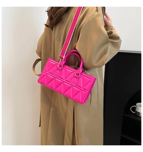 Detail of pink geometric quilted handbag showing wide shoulder strap and PU leather texture