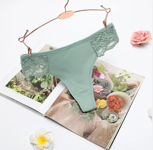 Detail of light green ribbed cotton thong with sheer floral lace panels on a gold hanger