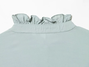 Detail shot of ruffle neck collar and stitching on the mint green viscose blouse