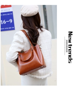 Close-up of brown leather tote bag texture with shoulder strap and top handle