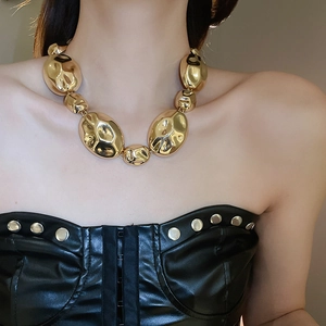 Detail of chunky gold necklace with irregular metal beads worn on female model
