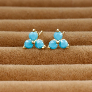 Detailed shot of clover stud earrings with blue faceted stones in gold-plated settings