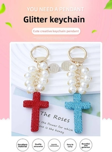 Macro detail of cross pendant keychain with pearls and lobster clasp on a pedestal