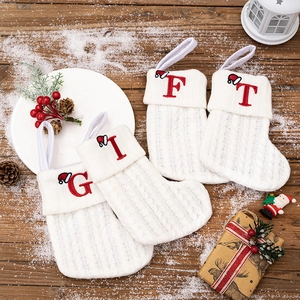 Set of 4 white knitted Christmas stockings with red embroidered GIFT letters on wood table