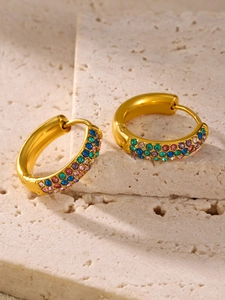 Macro view of gold-plated hoop earrings with multi-color zircon inlay on sand stone