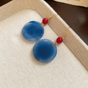 Détail de boucles d'oreilles rétro avec pendentifs en marbre bleu sur un plateau en lin
