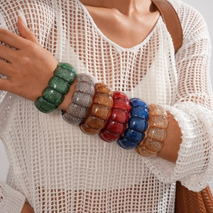 Close-up of colorful resin bracelets with glitter details worn by a model in layers
