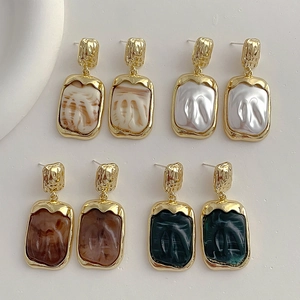 Detailed close-up of geometric resin cube earrings with textured gold metallic frames